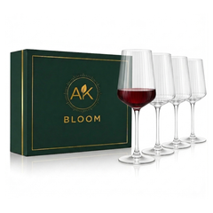 AK BLOOM set of 4 clear ribbed long stem wine glasses, one partially filled with red wine, displayed beside a dark green gift box with gold trim.